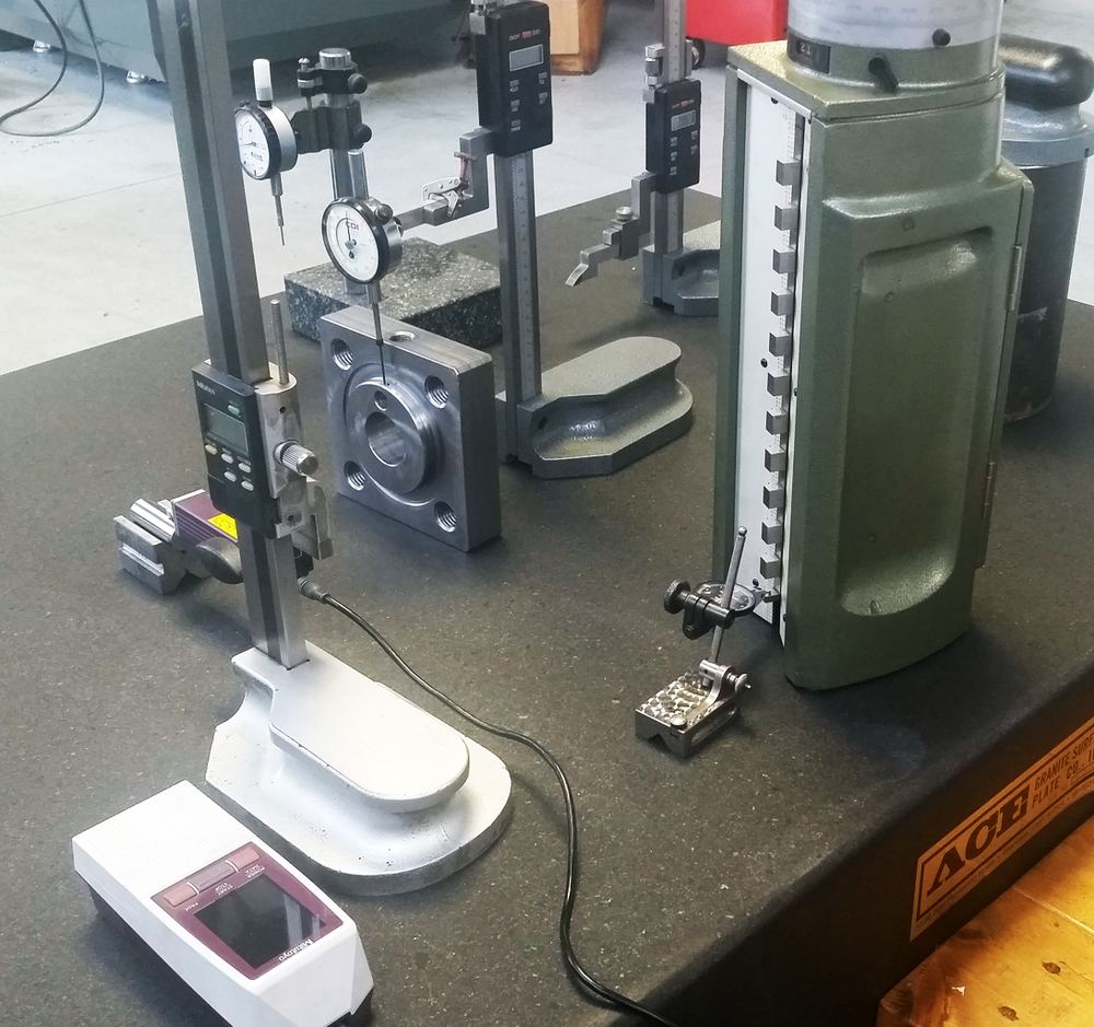 Height gauge and dial indicators on a granite inspection table