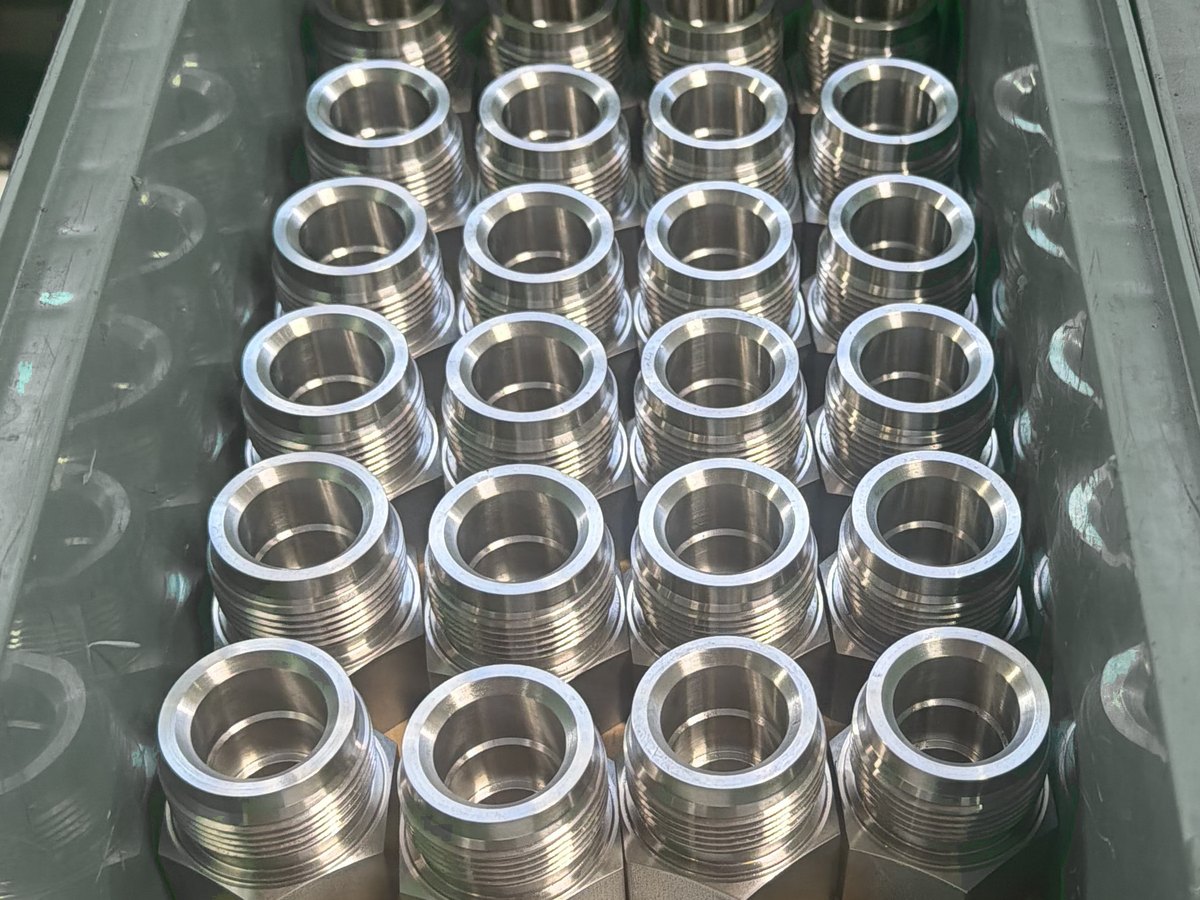 Bin of machined stainless fittings in rows